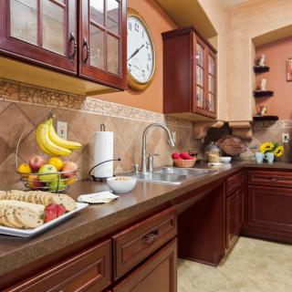 A warm and inviting kitchen with wooden cabinets, a fruit display, and elegant tile backsplash.