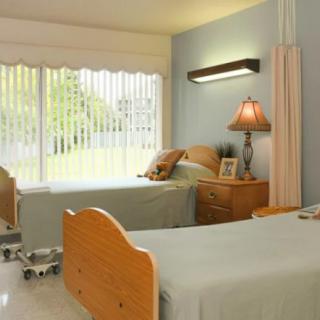 A well-lit hospital room with twin beds and cozy furnishings.
