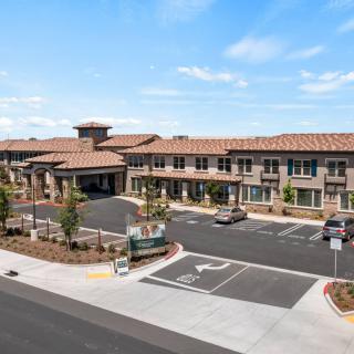 A modern commercial building with a spacious parking lot under a clear blue sky.