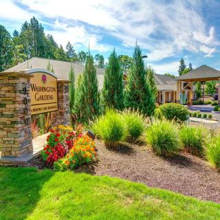 A beautiful landscaped garden with a stone sign and neatly manicured grounds in front of a building.