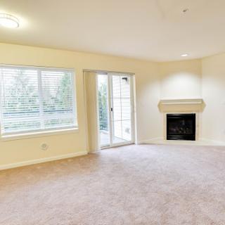 A spacious and empty living room featuring a cozy fireplace and large windows that provide natural light.