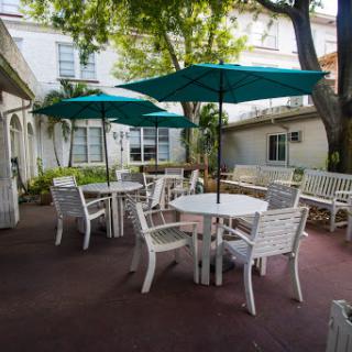 A cozy outdoor patio area with white furniture and teal umbrellas, perfect for enjoying a peaceful moment.