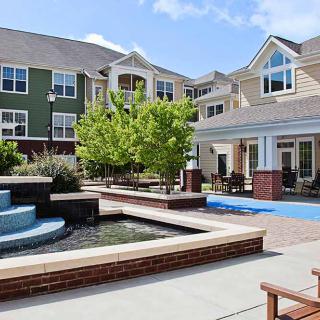 An inviting courtyard featuring a water fountain and seating areas surrounded by modern apartment buildings.