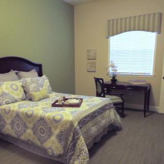 A cozy bedroom with a single bed, desk, and window with curtains.
