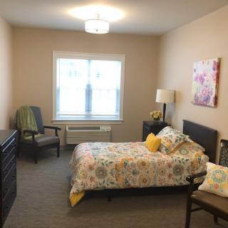 A cozy bedroom with a single bed, a chair, and decorative elements.