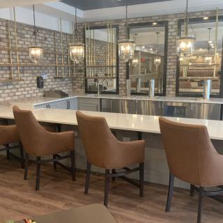 A modern kitchen interior featuring a counter with bar stools and decorative pendant lighting against a brick wall backdrop.