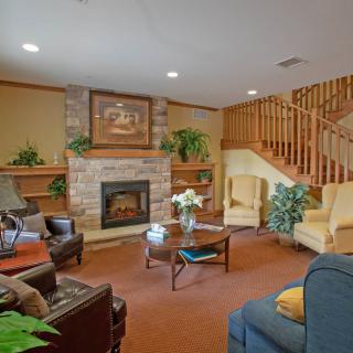 A cozy living room featuring a fireplace, comfortable seating, and a wooden staircase.