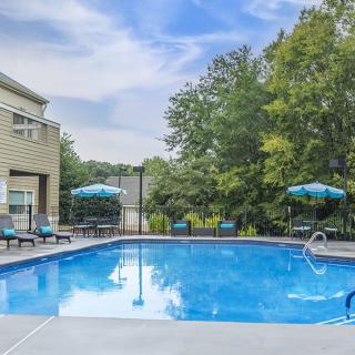 A serene outdoor swimming pool area with sun loungers and umbrellas under a clear sky.