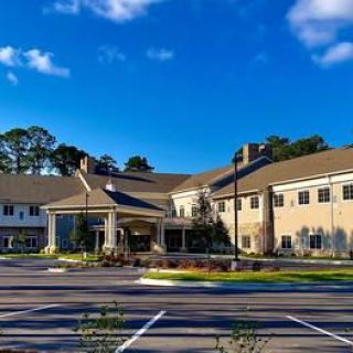 A residential-style building with a spacious parking lot under a clear blue sky.