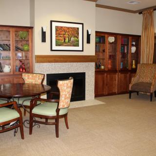 A cozy living room with a fireplace, dining table, and bookshelves.