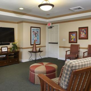 A cozy living room with comfortable seating, a television, and framed artwork on the walls.