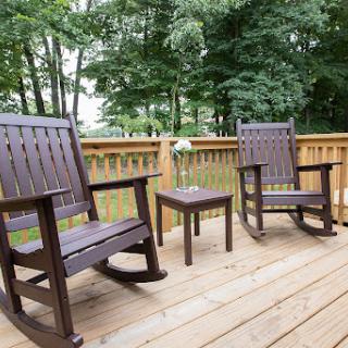 A serene outdoor space featuring two rocking chairs and a small table, perfect for enjoying nature.