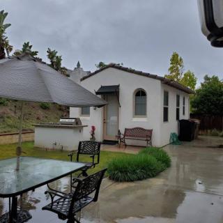 A small house with a backyard patio featuring a glass table and umbrella on a rainy day.