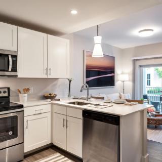A modern kitchen with white cabinets and stainless steel appliances, featuring a cozy dining area.