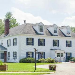 A large white suburban house with multiple dormer windows and a well-maintained lawn.