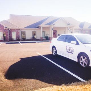 A white car parked in front of a residential building on a sunny day.