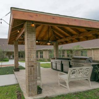 A cozy outdoor gazebo with brick columns and seating, perfect for gatherings.