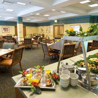 A neatly arranged buffet setup in a spacious dining room with tables and chairs.