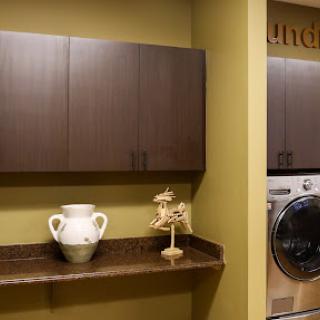 A stylish and modern laundry room featuring storage cabinets, a decorative vase, and a washing machine.