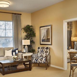 A cozy and stylish living room with modern decor, featuring a comfortable sofa, patterned armchair, elegant coffee table, and framed artwork.