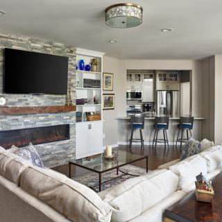 Modern living room with a stone fireplace, open kitchen, and contemporary decor.