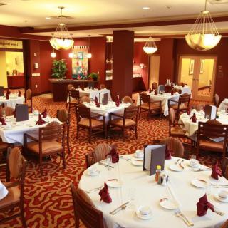 A well-appointed restaurant dining room with elegantly set tables and plush seating.