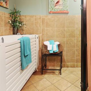 A cozy bathroom featuring tiled walls, a radiator with teal towels, and decor on the walls.