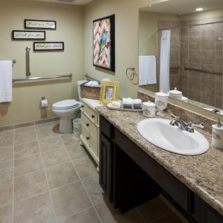 A well-decorated bathroom with a large mirror, sink, and toilet.