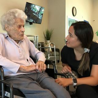 A nurse provides care and companionship to an elderly woman in a wheelchair.