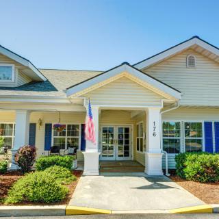 A welcoming entrance of a residential building with neatly landscaped surroundings and an American flag on display.