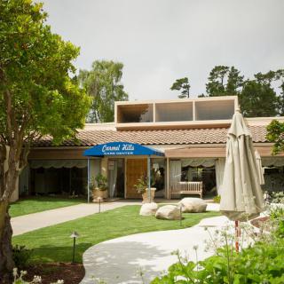 A welcoming entrance of a building with an awning, surrounded by trees and greenery.