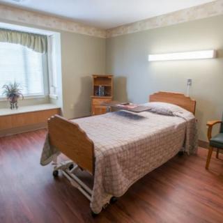 A clean and organized hospital room with a single bed and essential furniture.