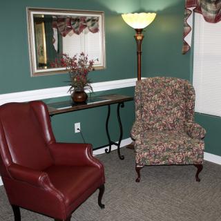 A cozy living room setup with two armchairs, a standing lamp, and a decorative mirror.