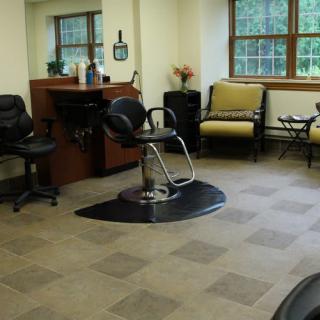 A cozy hair salon interior featuring styling chairs, a mirror, and a waiting area.