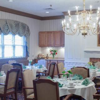 An elegant dining room with a chandelier, set tables, and decorated place settings.