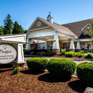 A well-landscaped building with a prominent entrance and a sign displaying its name.