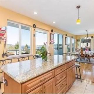 A spacious kitchen with a granite island, large windows, and a dining area bathed in natural light.