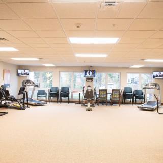 A well-lit gym with assorted fitness equipment and seating area.