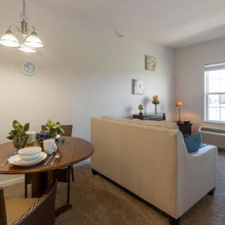 A cozy living and dining area with a sofa, table set, and natural light from the window.