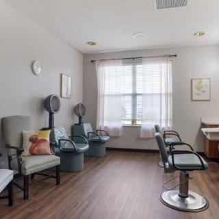 A cozy salon interior with chairs, hair dryers, and a large window.