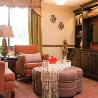 A cozy living room with comfortable armchairs, an ottoman, and a built-in bookshelf.