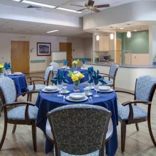 A beautifully set dining area featuring blue tablecloths and floral centerpieces, ideal for an inviting dining experience.