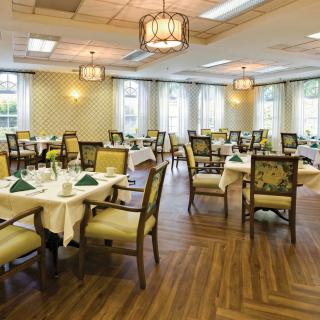 An elegant dining room with neatly arranged tables and chairs, featuring warm lighting and stylish decor.