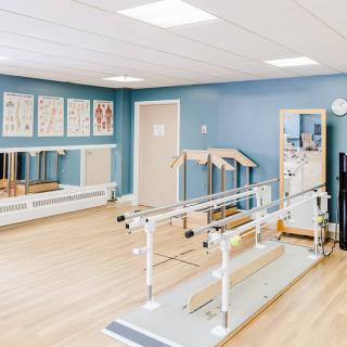 A physical therapy room with exercise equipment and parallel bars.