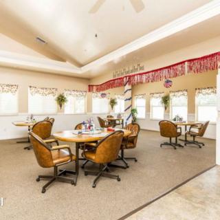 A bright and spacious dining area with several tables and chairs, decorated with festive banners and large windows allowing natural light to fill the room.
