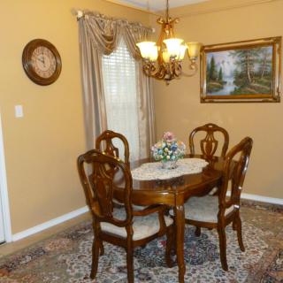 A traditional dining room with a wooden table set, ornate chandelier, and decorative wall art.