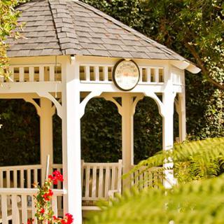 A charming white gazebo set amidst lush greenery in a garden.