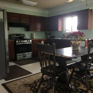 A cozy kitchen with a dining table and chairs, featuring modern appliances and wooden cabinets.