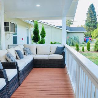A cozy porch with comfortable outdoor seating and a view of a well-maintained backyard garden.