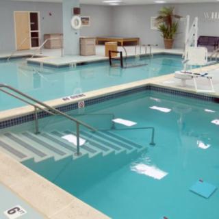 An indoor hydrotherapy facility equipped with a pool and therapy equipment for rehabilitation exercises.